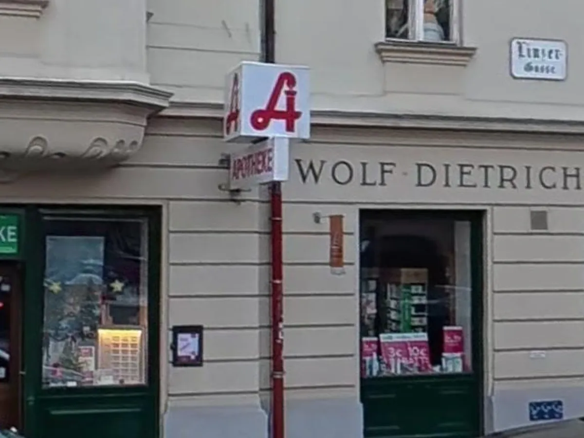 Schaufenster der Wolf-Dietrich-Apotheke mit dem roten Apotheken-A und dem Straßenschild Linzer Gasse